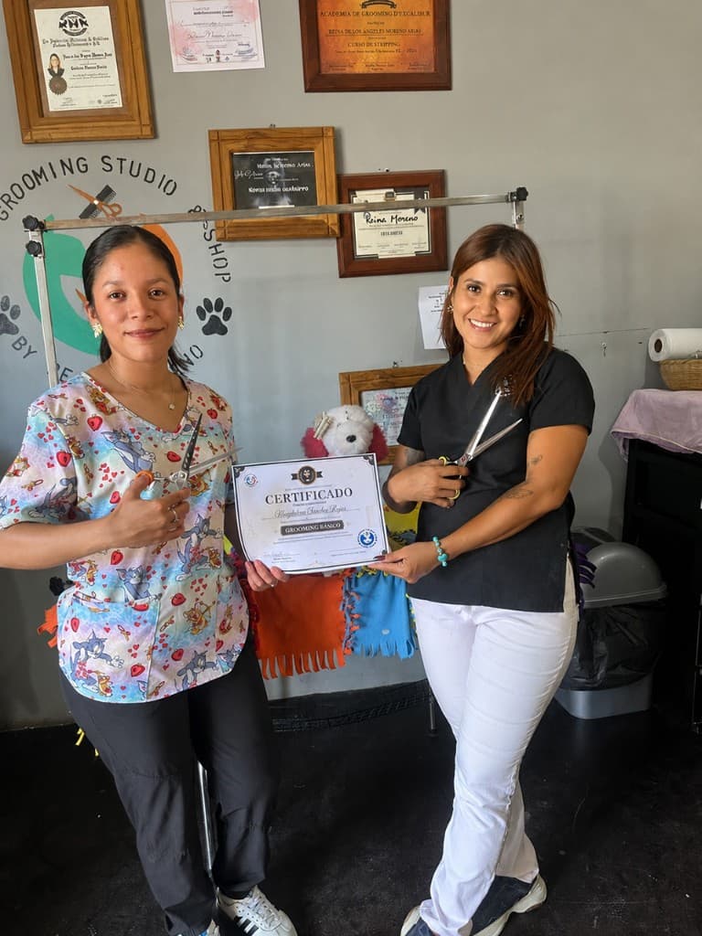 Reina presenting a basic grooming course certificate to a graduate at Royal Paws Studio
